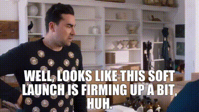 Two white men are talking with each other. One is the man (David) from the previous image. The other (Patrick) is brown-haired and wearing a blue button down. He is saying, "Well, looks like this soft launch is firming up a bit, huh?"